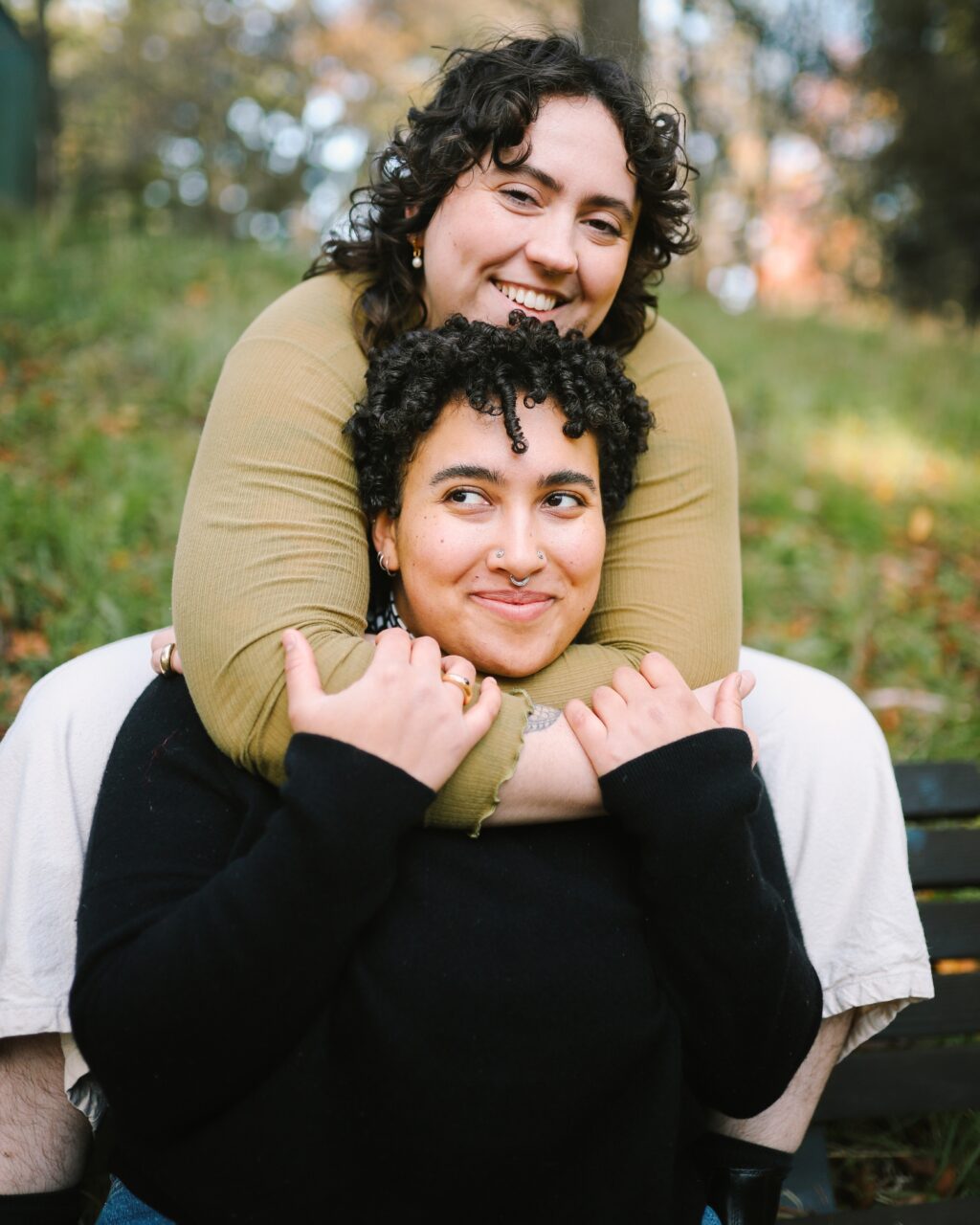 A queer couple is embracing and smiling at a park together. Start body image therapy in Orange County today.