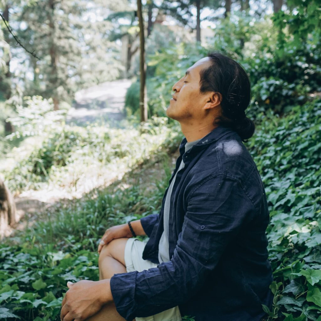 A person sits in a forest while breathing deep with their eyes closed. This could represent the benefits of nature in addressing past trauma. Learn how a trauma therapist in Los Angeles, CA can offer support by searching for relationship issues in CA